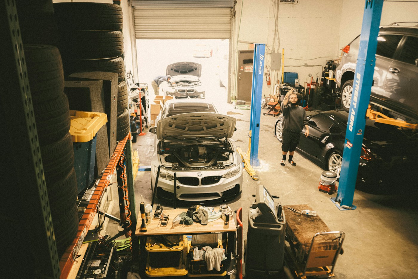 Mechanic working beside a car with its hood open in a workshop